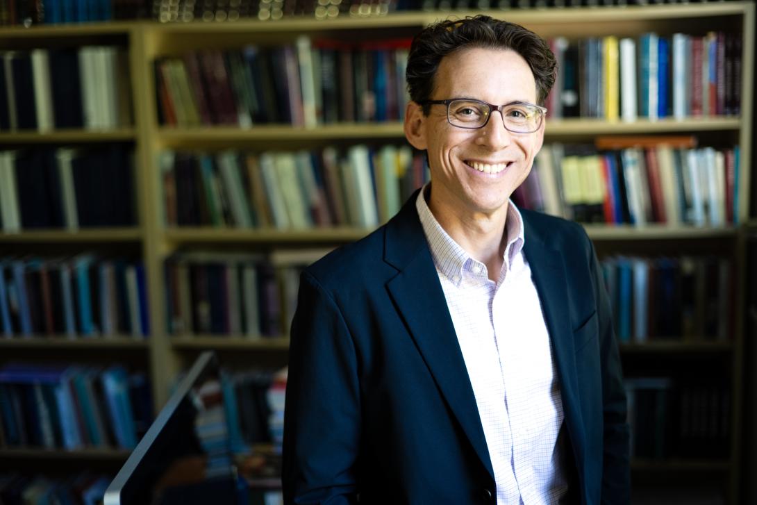 Hartley Lachter smiles at camera in front of a bookcase